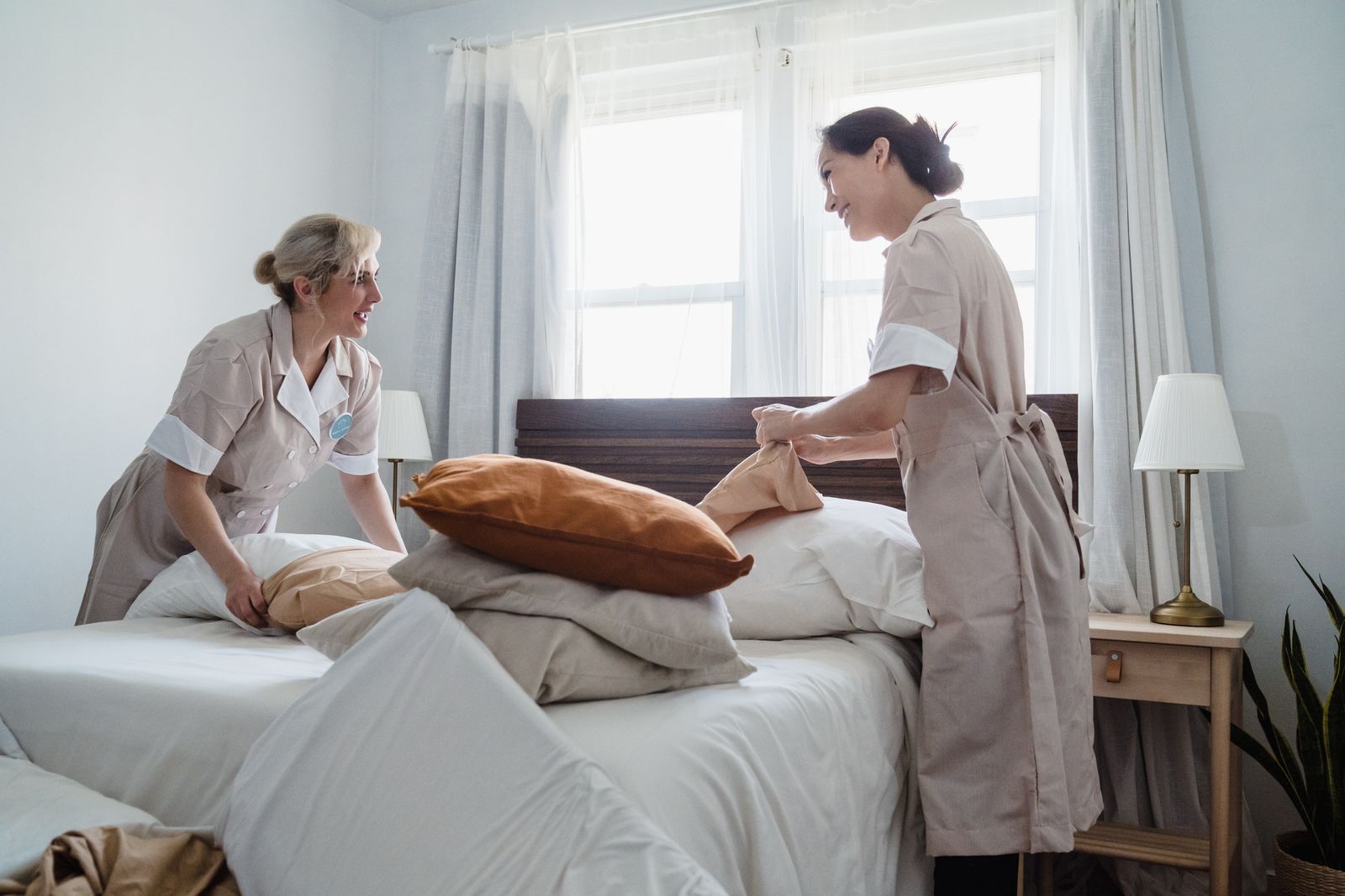 Two Brightwell housekeepers making a bed in a bright bedroom